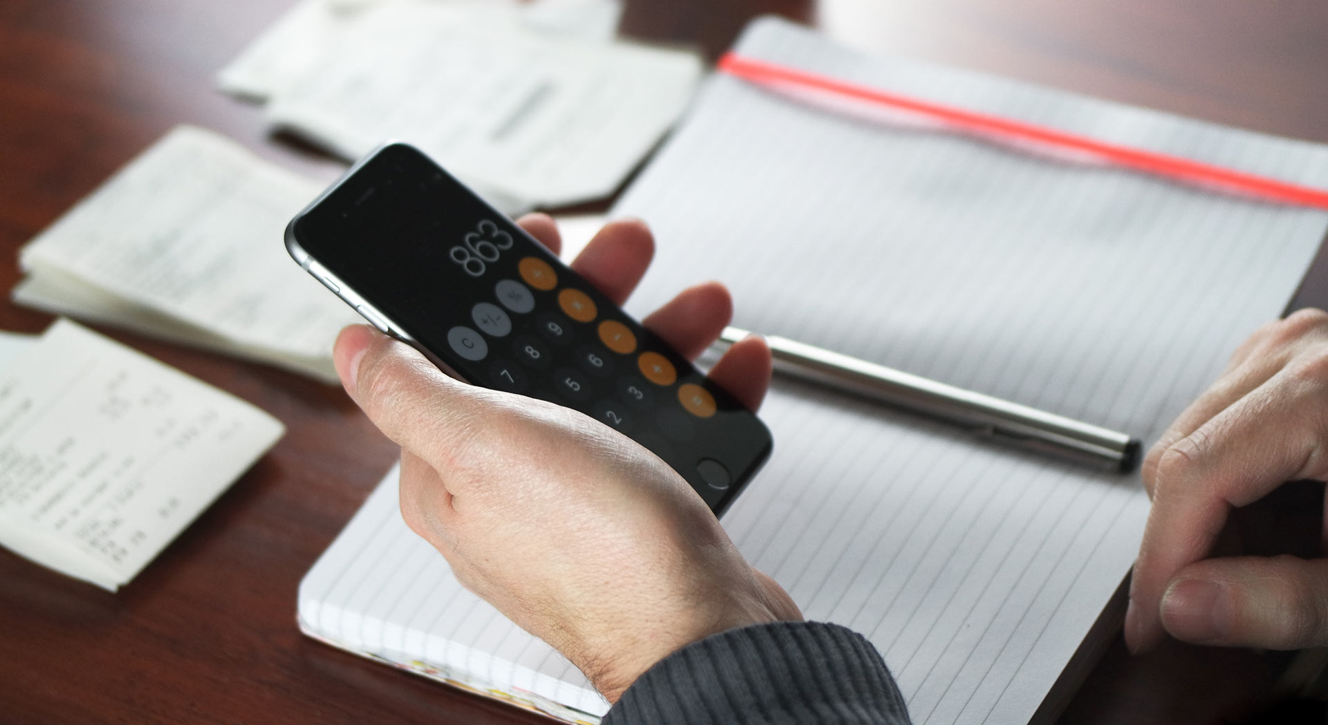 person working in a ledger using a calculator app on a smart phone